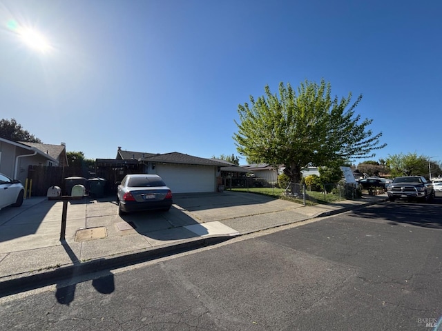 view of front of property featuring concrete driveway, an attached garage, and fence