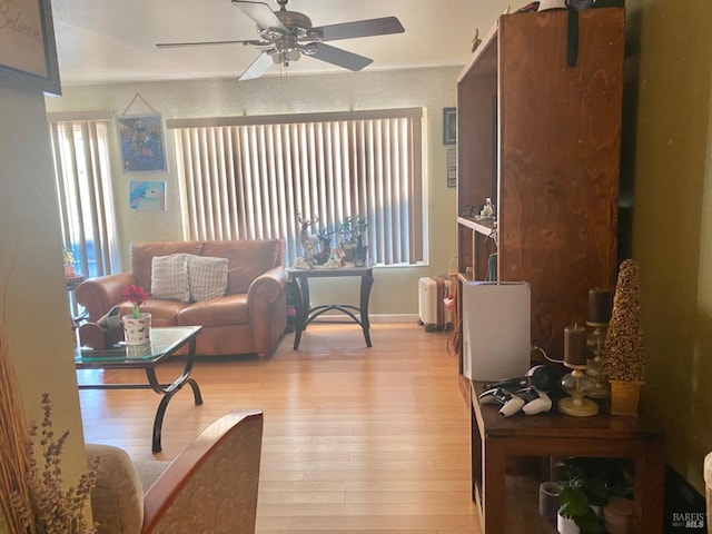 living room featuring light wood-type flooring, a ceiling fan, and radiator