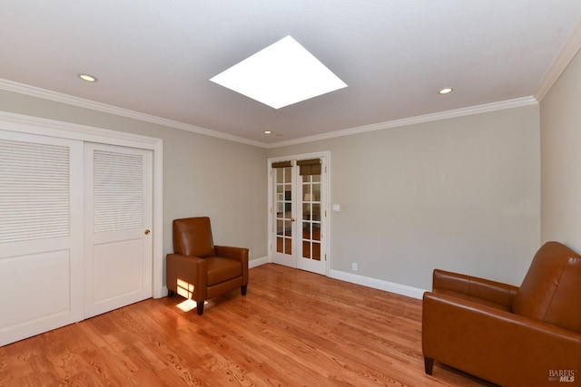 living area with french doors, a skylight, ornamental molding, and light hardwood / wood-style flooring