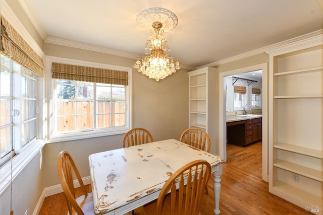 dining area with a chandelier, ornamental molding, light hardwood / wood-style flooring, and sink