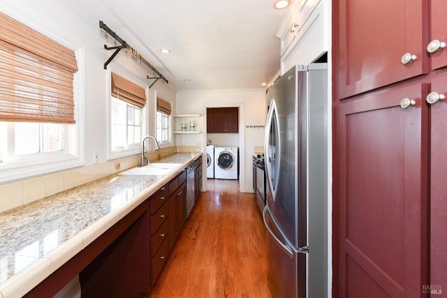 kitchen featuring dark wood-type flooring, stainless steel appliances, sink, ornamental molding, and independent washer and dryer