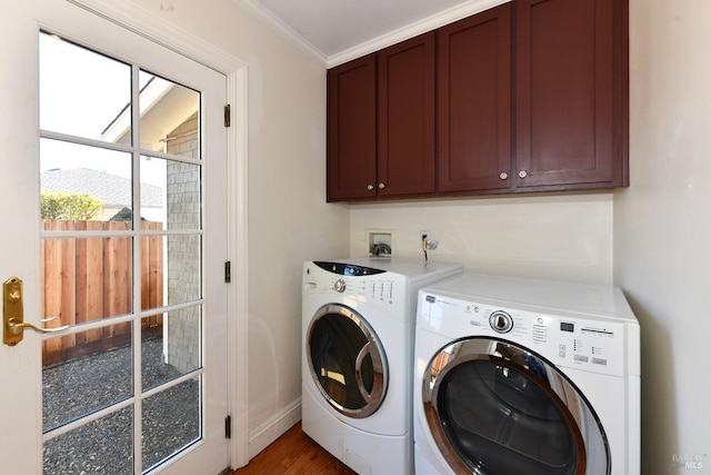 clothes washing area featuring dark wood-type flooring, washer and dryer, crown molding, and cabinets