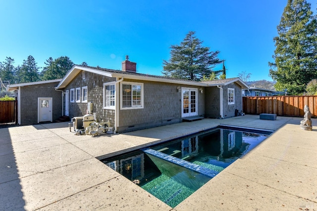 rear view of property with french doors, a patio area, and a fenced in pool