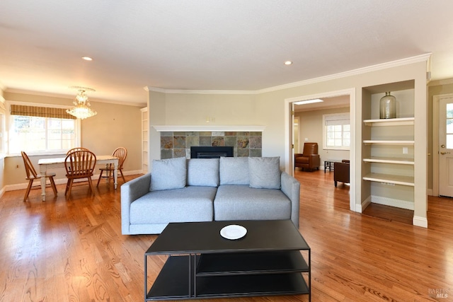 living room with a fireplace, wood-type flooring, built in features, and crown molding