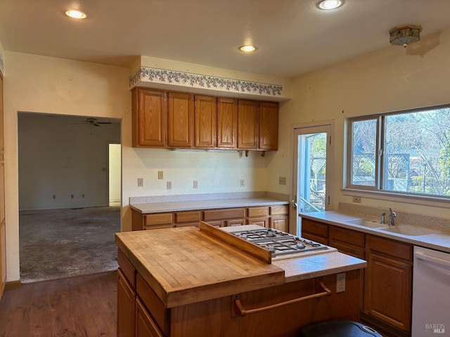 kitchen featuring dark hardwood / wood-style floors, a center island, sink, white dishwasher, and stainless steel gas cooktop