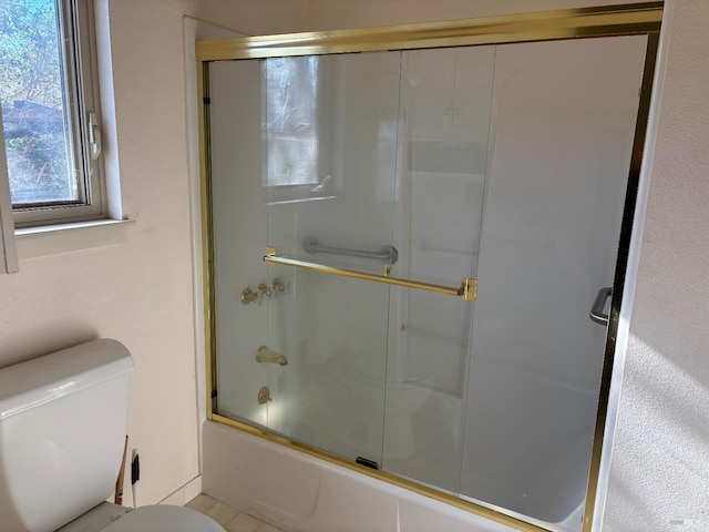 bathroom featuring toilet, combined bath / shower with glass door, and tile patterned flooring