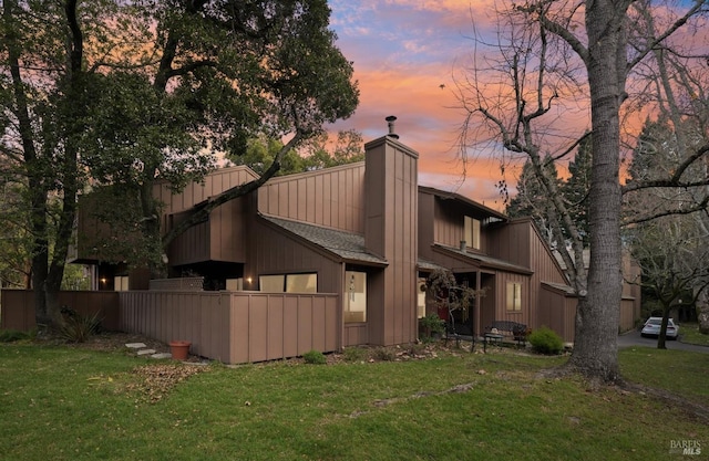 back house at dusk featuring a yard