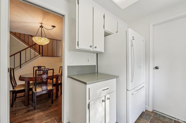 kitchen with a textured ceiling, white refrigerator, white cabinetry, and pendant lighting