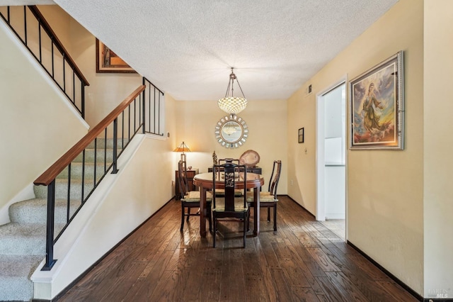 dining space with dark wood-type flooring and a textured ceiling