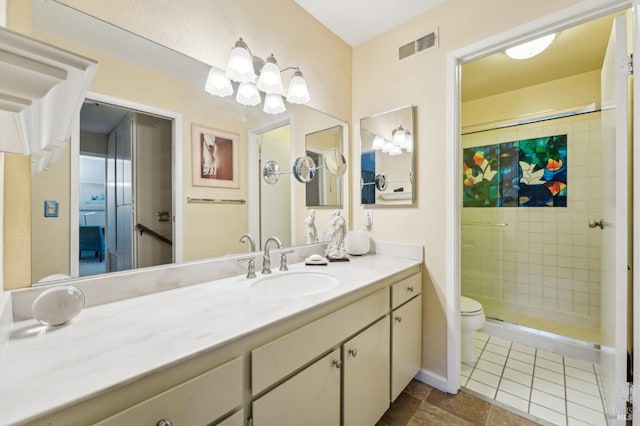 bathroom featuring toilet, vanity, a tile shower, and tile patterned flooring