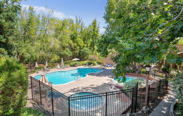 view of swimming pool featuring a community hot tub and a patio area