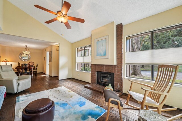 living room with vaulted ceiling, ceiling fan, dark hardwood / wood-style flooring, a fireplace, and a textured ceiling