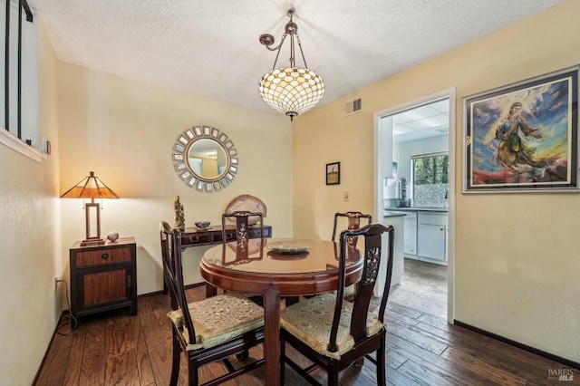 dining area with a textured ceiling and dark hardwood / wood-style flooring