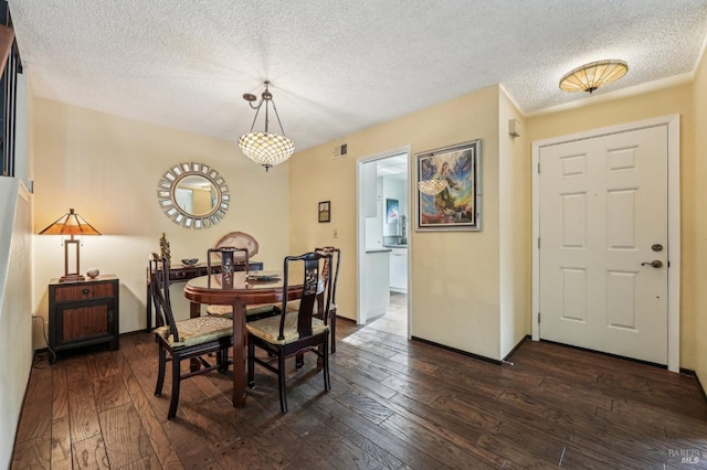 dining space with dark wood-type flooring and a textured ceiling