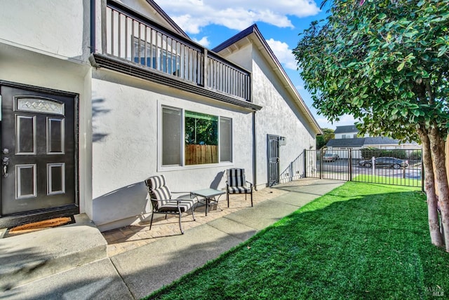 rear view of house featuring a balcony and a yard