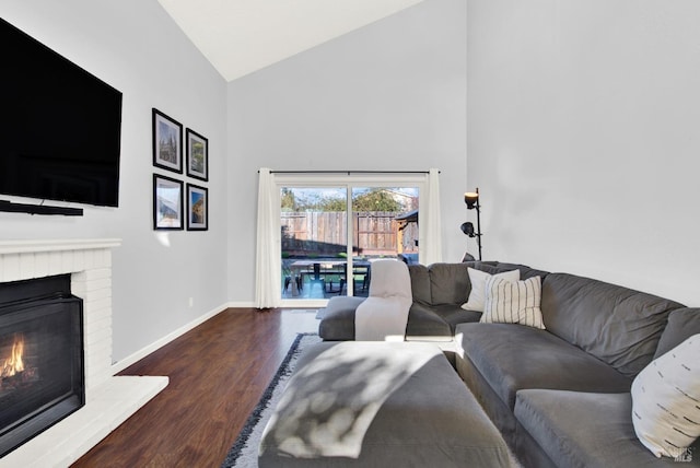 living room featuring a brick fireplace, dark hardwood / wood-style flooring, and high vaulted ceiling