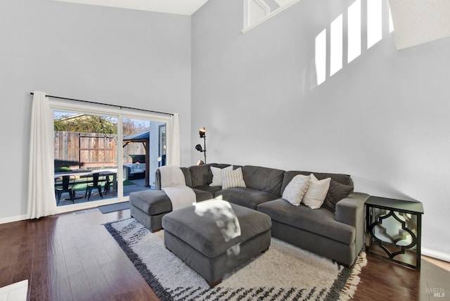 living room featuring dark wood-type flooring and a towering ceiling