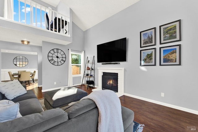 living room featuring high vaulted ceiling, dark hardwood / wood-style floors, and a brick fireplace