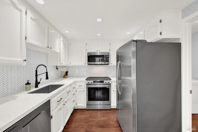 kitchen featuring white cabinetry, stainless steel appliances, decorative backsplash, dark wood-type flooring, and sink