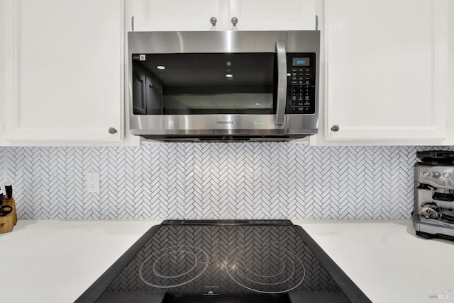 kitchen with backsplash, light stone counters, and white cabinetry