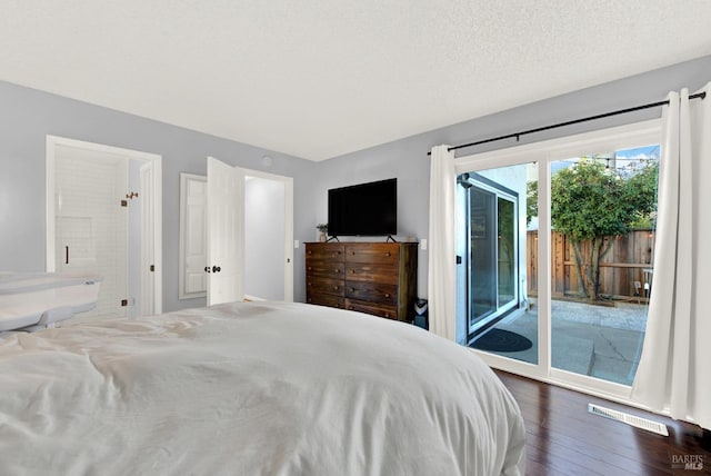 bedroom featuring connected bathroom, dark hardwood / wood-style floors, access to outside, and a textured ceiling