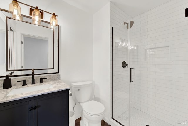 bathroom featuring toilet, vanity, and an enclosed shower