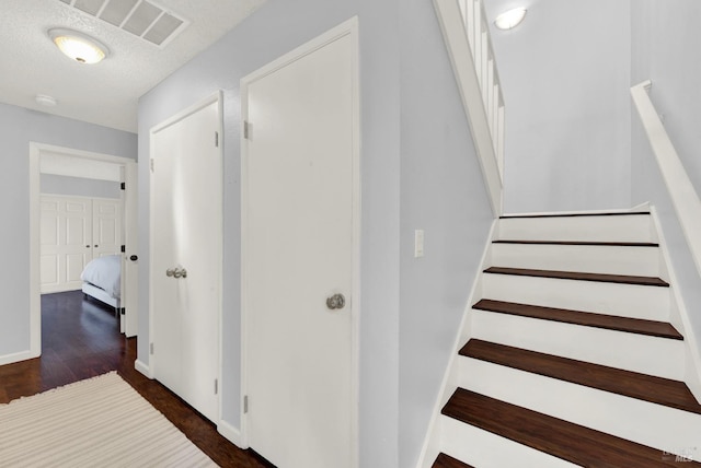 stairs featuring a textured ceiling and hardwood / wood-style flooring