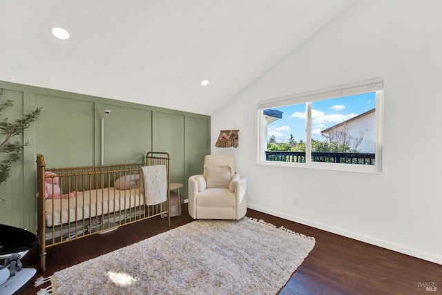 bedroom featuring lofted ceiling, a nursery area, and dark wood-type flooring