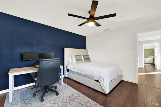 bedroom with a textured ceiling, ceiling fan, and dark hardwood / wood-style floors