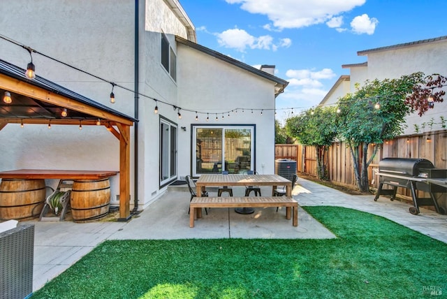 back of property with a lawn, a hot tub, and a patio area