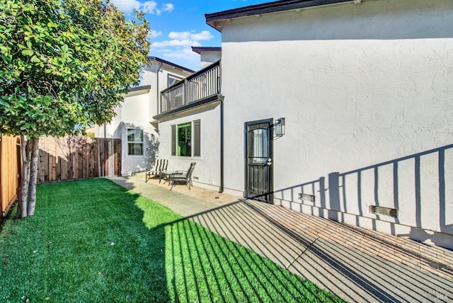 rear view of property featuring a yard, a patio area, and a balcony