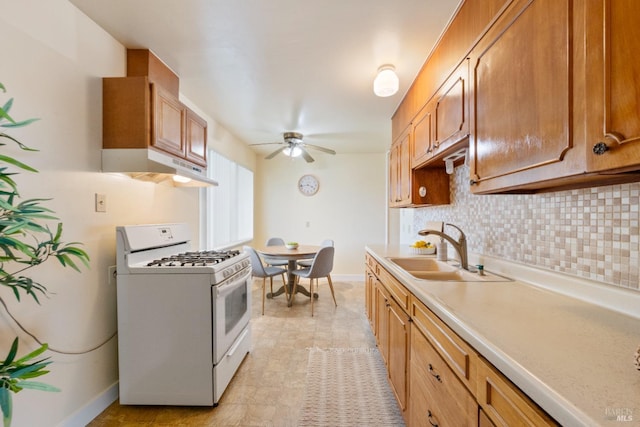 kitchen with sink, decorative backsplash, ceiling fan, and white gas range oven