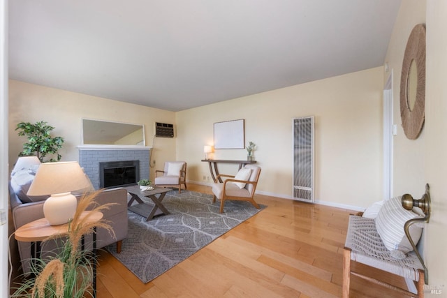 living room with wood-type flooring, a fireplace, and an AC wall unit