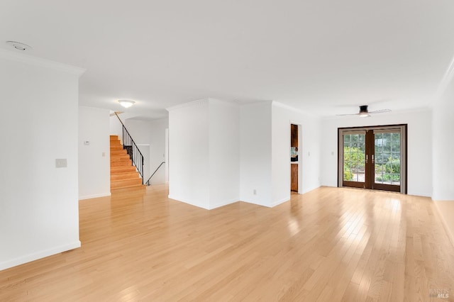 empty room with ornamental molding, french doors, ceiling fan, and light wood-type flooring