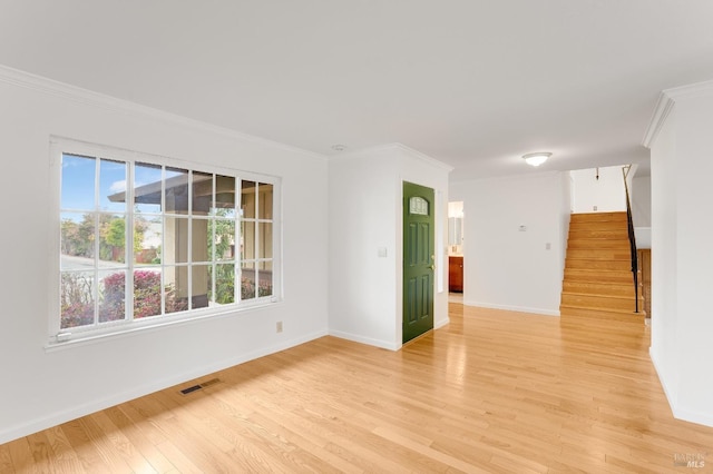 empty room with ornamental molding and light hardwood / wood-style flooring