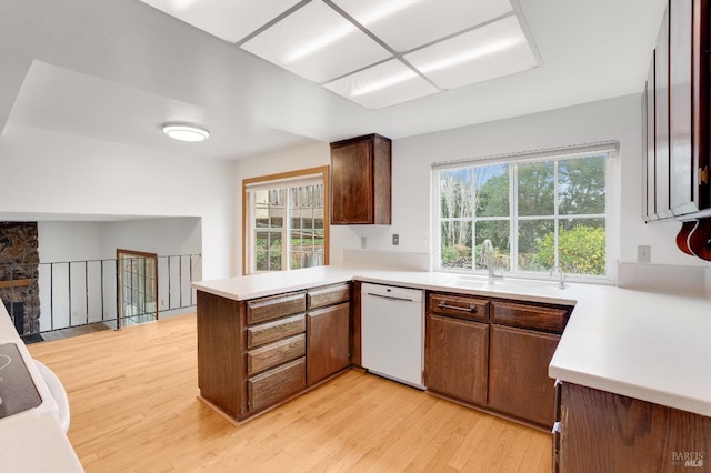 kitchen featuring dishwasher, sink, light wood-type flooring, and kitchen peninsula