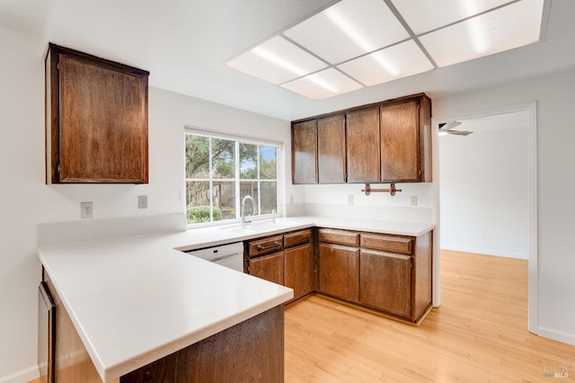 kitchen featuring white dishwasher, sink, light hardwood / wood-style flooring, and kitchen peninsula