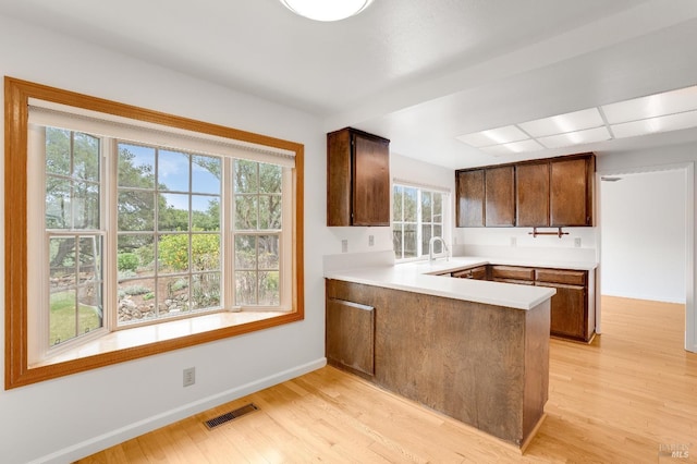 kitchen with sink, light hardwood / wood-style flooring, and kitchen peninsula