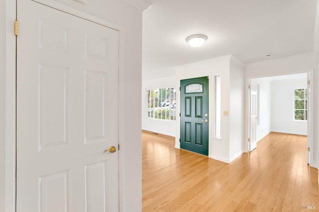 hallway featuring crown molding and light hardwood / wood-style flooring