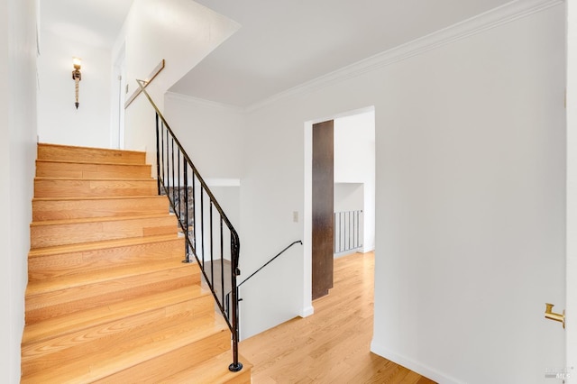 staircase with hardwood / wood-style flooring and ornamental molding