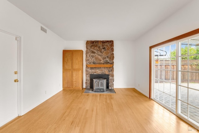 unfurnished living room featuring a wood stove and light wood-type flooring