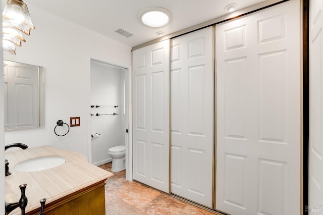 bathroom with ornamental molding, vanity, and toilet