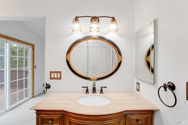 bathroom with crown molding, vanity, and vaulted ceiling