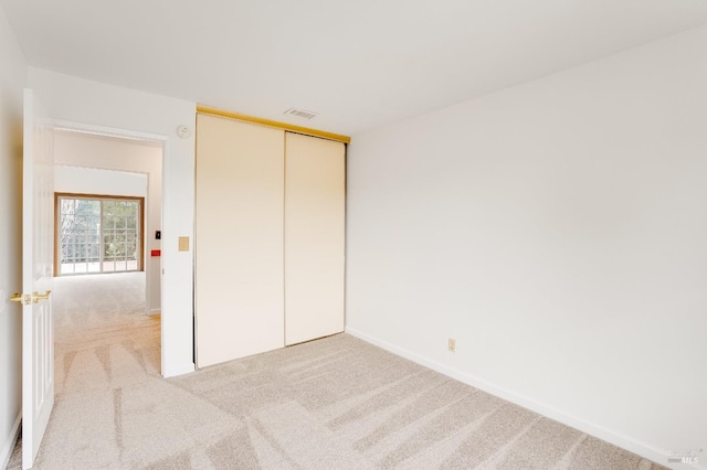 unfurnished bedroom with light colored carpet, a closet, and elevator