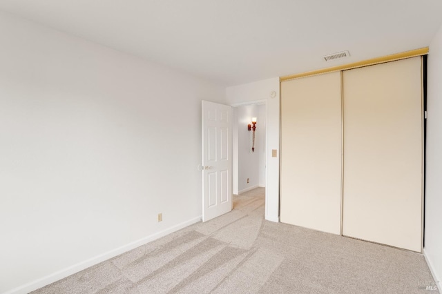 unfurnished bedroom with light colored carpet and a closet