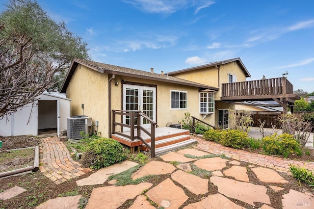 rear view of house featuring a deck, a storage unit, central air condition unit, a patio area, and french doors