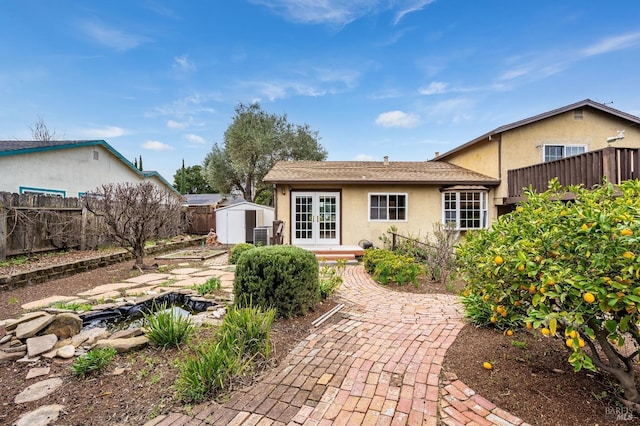 back of property with french doors and a storage unit