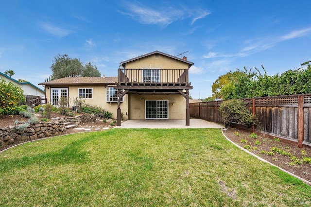 rear view of property featuring a balcony, a yard, and a patio area