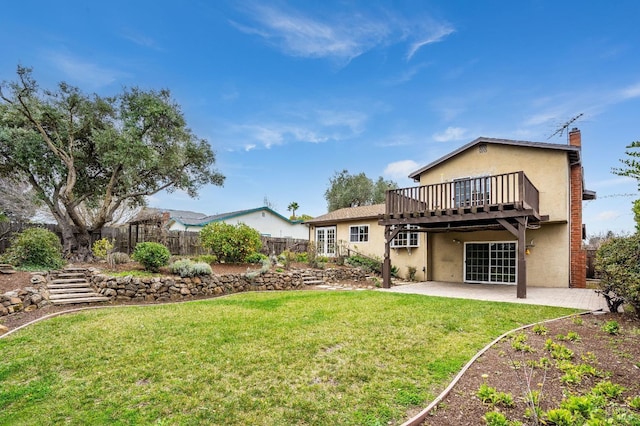 rear view of property featuring a wooden deck, a yard, and a patio area