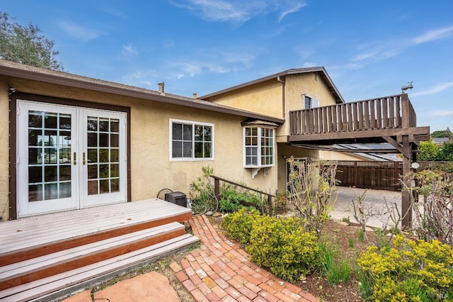 rear view of property featuring a wooden deck, a patio area, and french doors